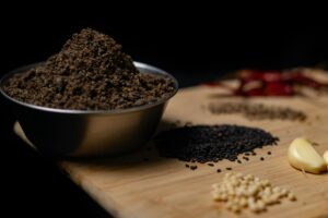 pexels-photo-32144885-32144885 Close-up of assorted spices including black sesame and garlic on a wooden board.