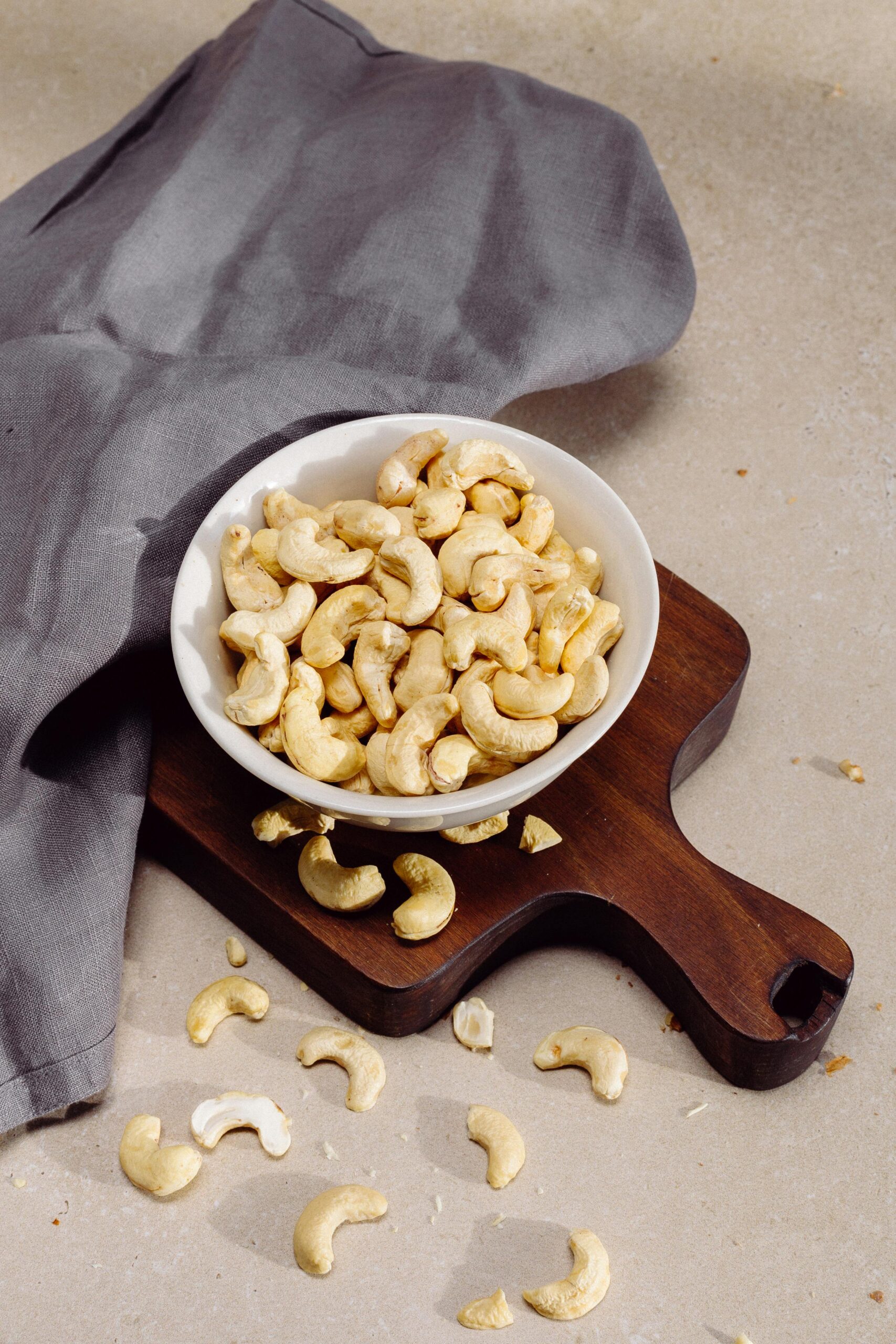 Best Cashew in Udhana Top view of cashew nuts in a bowl on a wooden cutting board, perfect for healthy snack concepts.