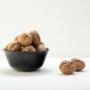 A classic arrangement of whole walnuts in a black bowl on a white surface, offering elegant culinary visuals.