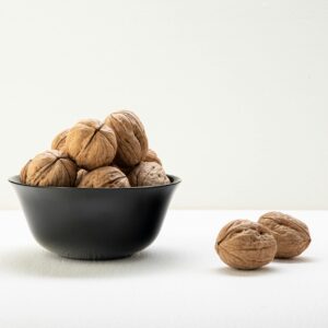 Home A classic arrangement of whole walnuts in a black bowl on a white surface, offering elegant culinary visuals.